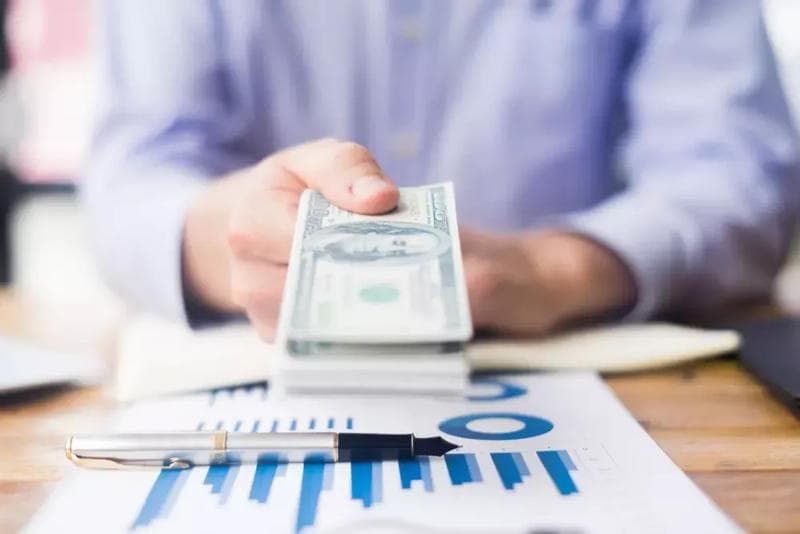 Pessoa segurando um maço de notas de dólar